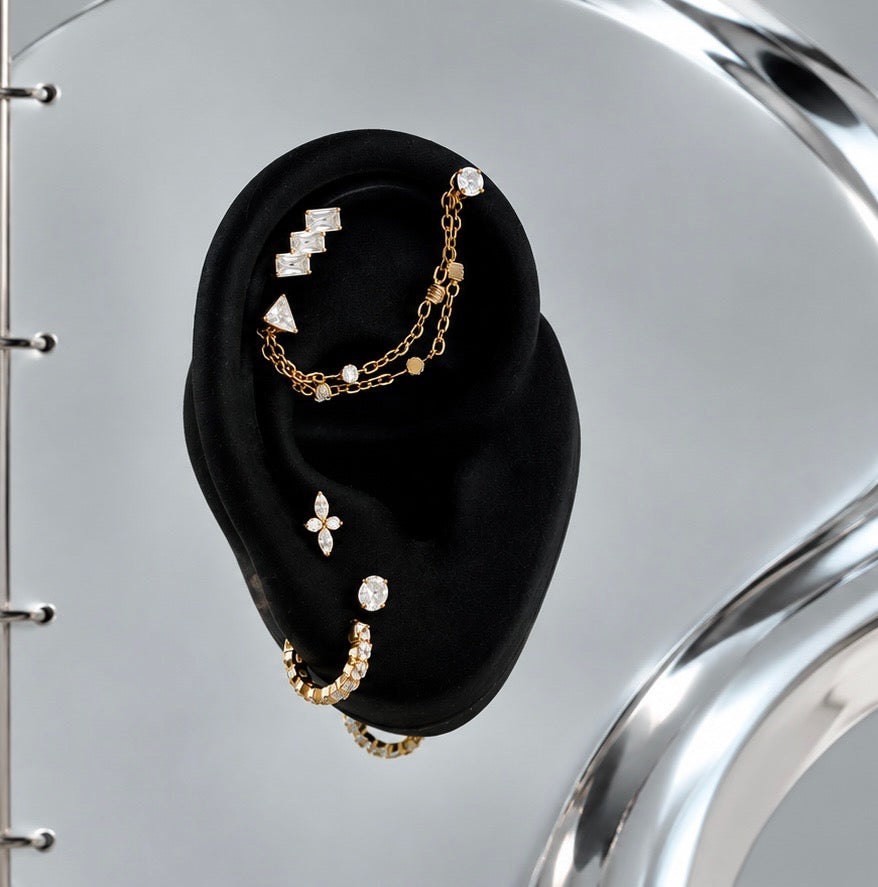Aurelai gold titanium and CZ earrings and chain styled on a black display ear