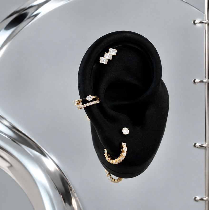Aurelai gold titanium and CZ earrings and chain styled on a black display ear