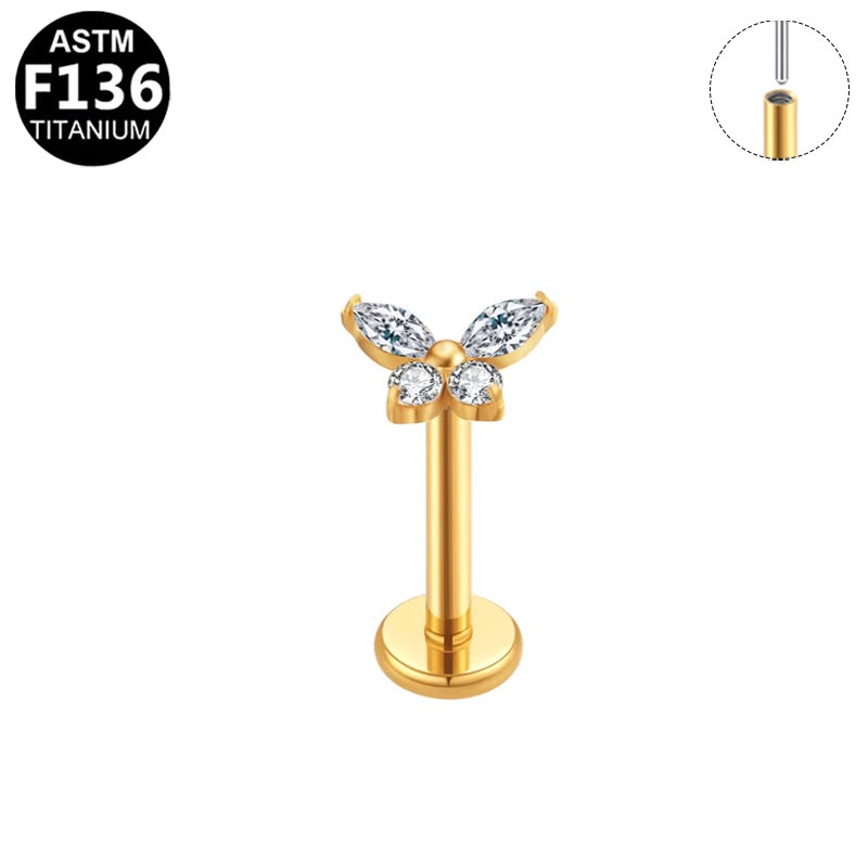 Gold butterfly-shaped labret piercing stud with clear marquise-cut gemstones, shown on a white background with an ASTM F136 titanium badge and a wire inset diagram.