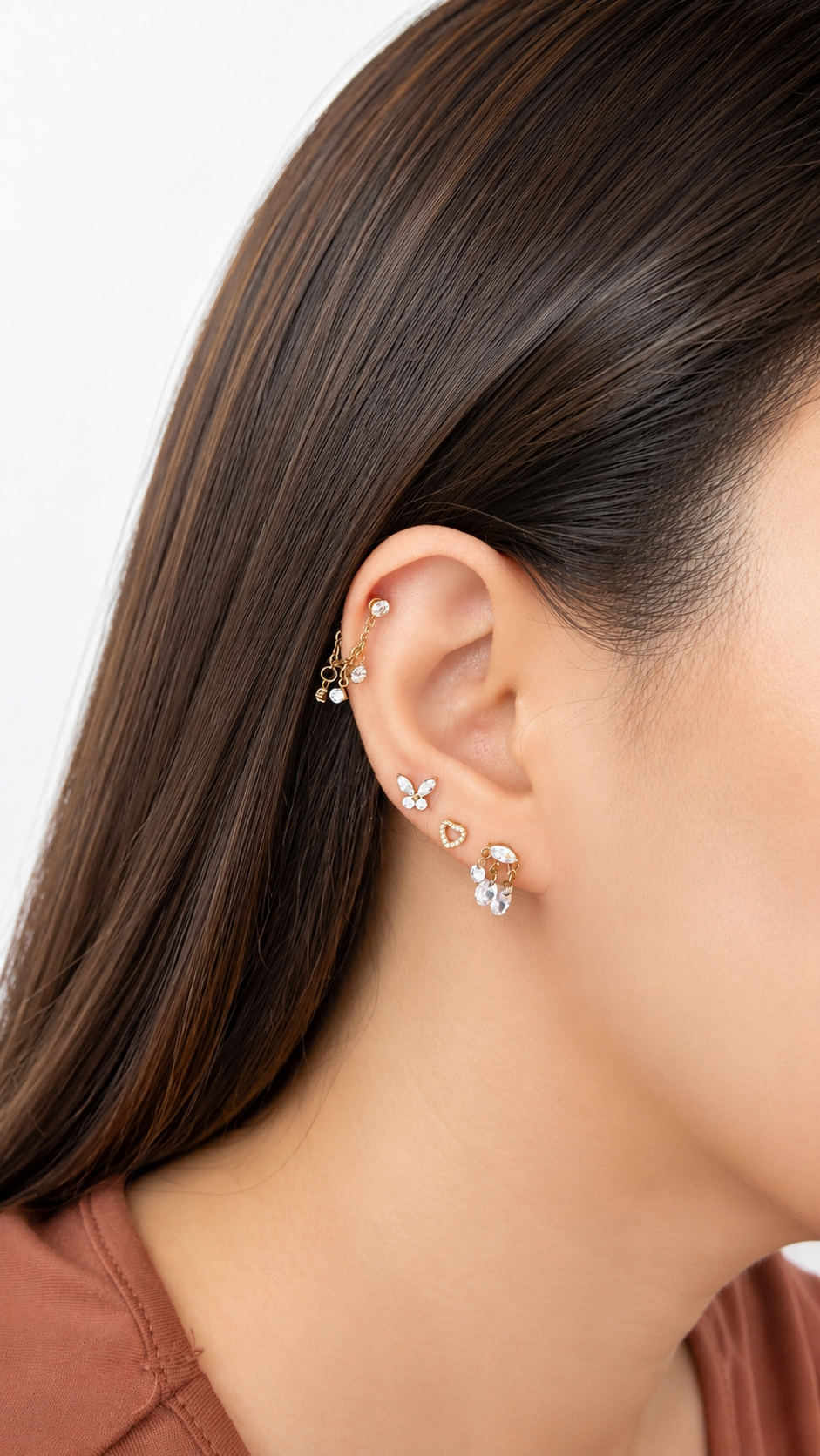 A close up image of a woman wearing titanium butterfly, heart, cluster earring, solitaire and Titanium chain connector with CZ raindrop charms.