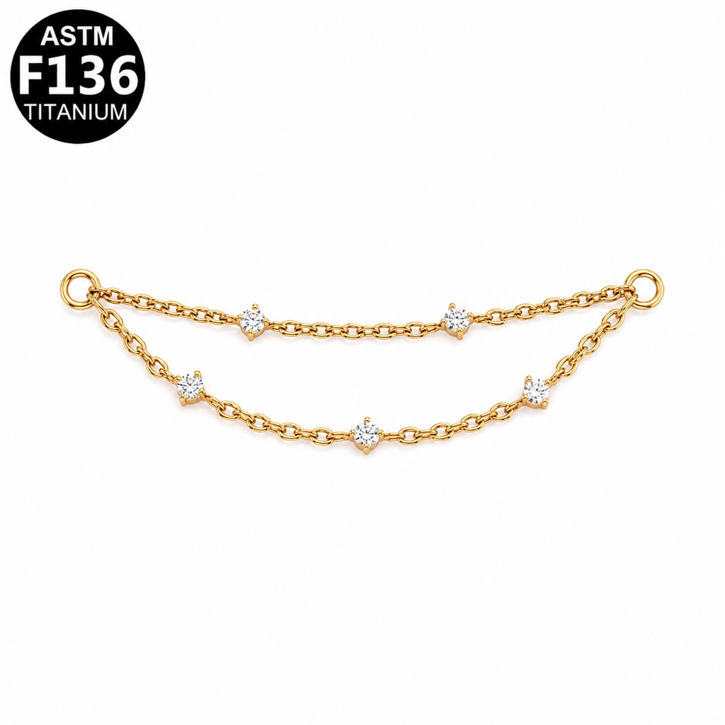 A gold-toned double-chain bracelet with small solitaire, star-shaped clear gemstone accents, shown on a white background with an ASTM F136 Titanium badge in the top-left corner.
