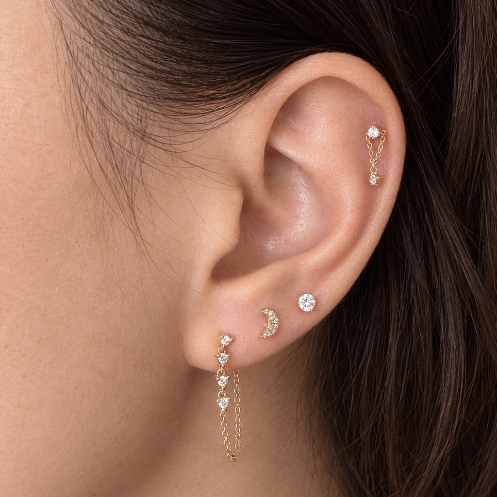 Ear stack with gold chain drop earring, crescent moon stud and CZ solitaires on a model's ear