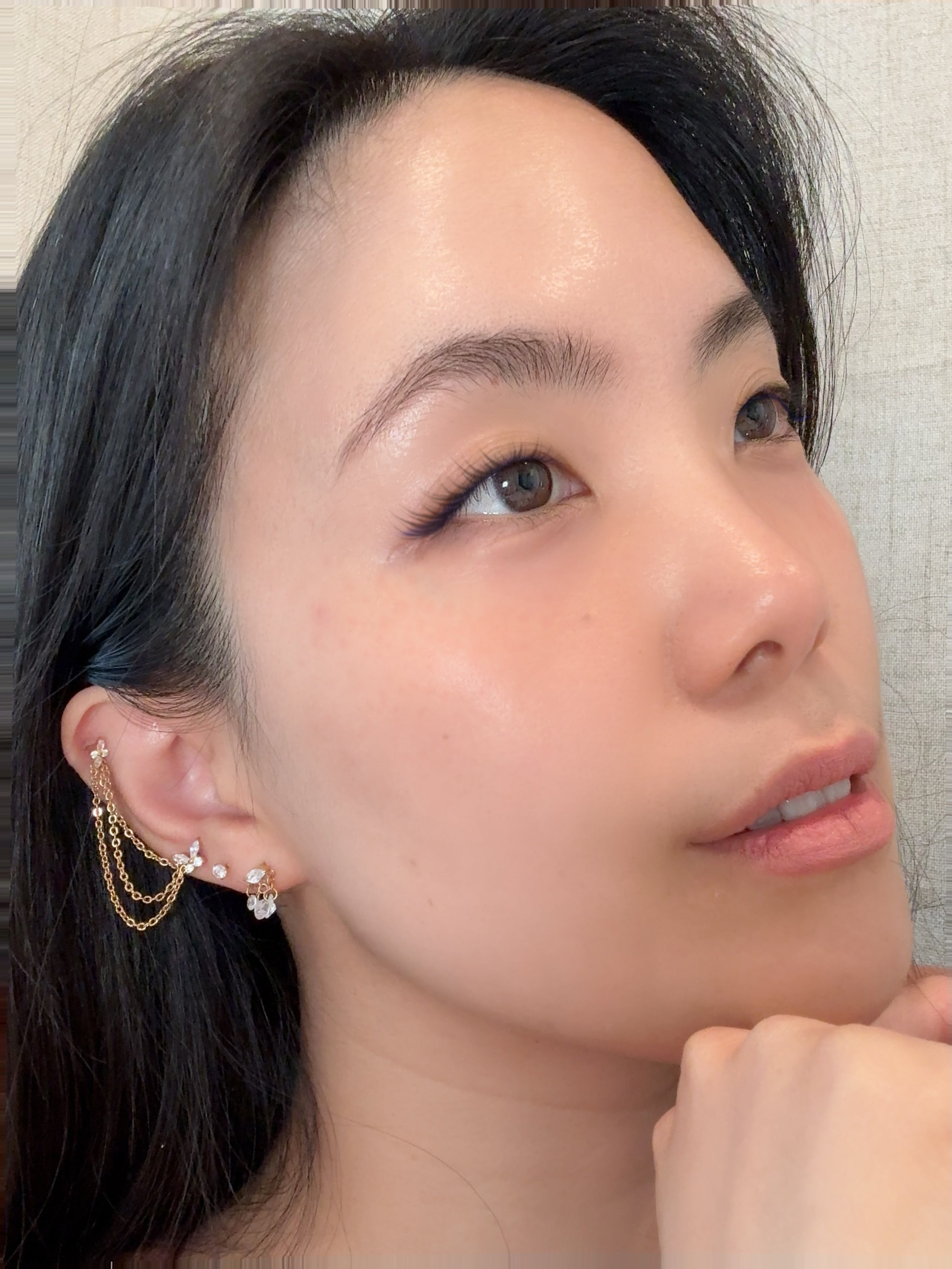 Woman wearing a gold-toned titanium double-strand chain accessory, butterfly, solitaire and cluster eattings.